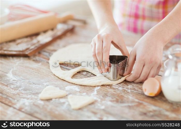 cooking and home concept - close up of female hands making cookies from fresh dough at home