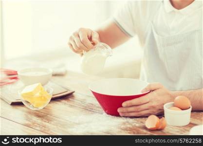 cooking and home concept - close up of male hand pouring milk in bowl