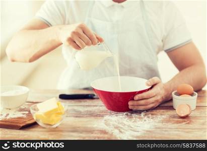 cooking and home concept - close up of male hand pouring milk in bowl