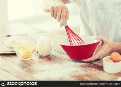 cooking and home concept - close up of male hand whisking something in a bowl
