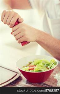 cooking and home concept - close up of male hands flavouring salad in a bowl