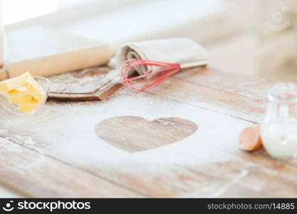 cooking and love concept - close up of heart of flour on wooden table at home