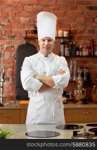 cooking and people concept - happy male chef cook with crossed hands in restaurant kitchen