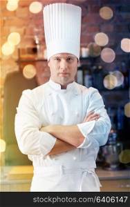 cooking and people concept - happy male chef cook with crossed hands in restaurant kitchen. happy male chef cook in restaurant kitchen