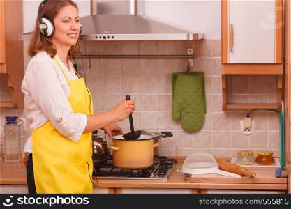 Cooking and preparing food concept. Happy relaxed beauty woman housewife chef with earphones listening music in house kitchen making dinner meal.