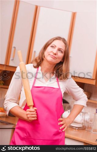 Cooking and preparing food meal concept. Thoughtful wondering and dreaming woman chef cook housewife holding rolling pin in kitchen.. Housewife with rolling pin in kitchen