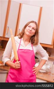Cooking and preparing food meal concept. Thoughtful wondering and dreaming woman chef cook housewife holding rolling pin in kitchen.. Housewife with rolling pin in kitchen