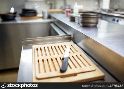 cooking and public catering concept - cutting board and knife at restaurant kitchen. cutting board and knife at restaurant kitchen