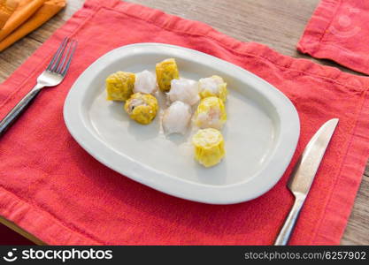 cooking, asian kitchen and food concept - plate of spring rolls with rice, fork and knife on wooden table at restaurant