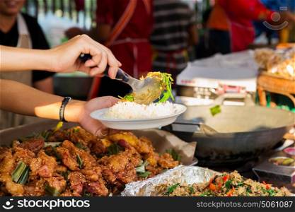 cooking, asian kitchen, people and food sale concept - seller hands with plate of rice serving chilly wok or pilaf dish at street market. seller with rice and wok food at street market