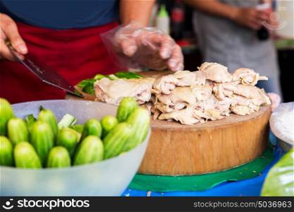 cooking, asian kitchen, people and food sale - cook with poultry and cucumbers at street market. cook with poultry and cucumbers at street market