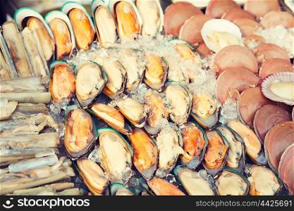 cooking, asian kitchen, sale and food concept - chilled oysters or seafood on ice at street market