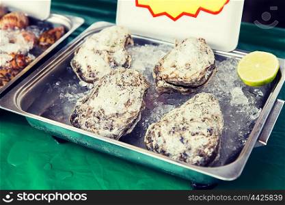 cooking, asian kitchen, sale and food concept - chilled oysters or seafood on ice at street market