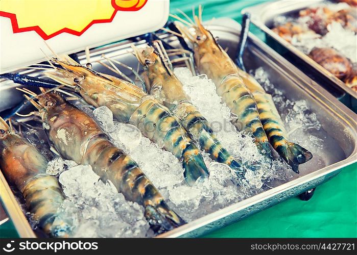 cooking, asian kitchen, sale and food concept - chilled shrimps or seafood on ice at street market