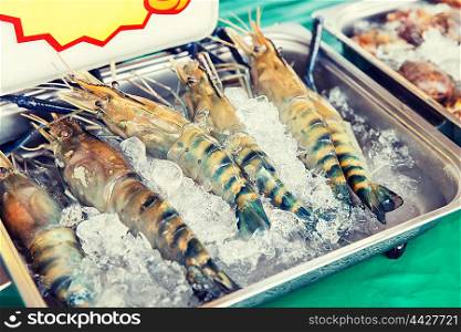 cooking, asian kitchen, sale and food concept - chilled shrimps or seafood on ice at street market