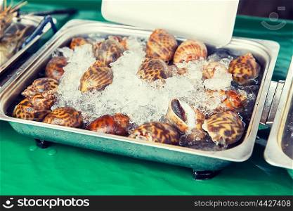 cooking, asian kitchen, sale and food concept - chilled snails or seafood on ice at street market