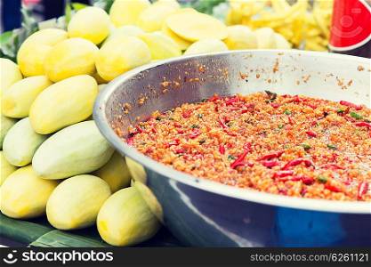 cooking, asian kitchen, sale and food concept - chilly wok or pilaf and mango at street market