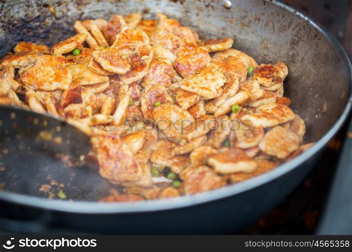 cooking, asian kitchen, sale and food concept - close up of meat frying in wok pan at street market