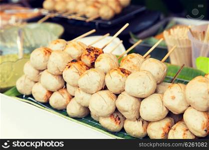 cooking, asian kitchen, sale and food concept - meatballs at street market