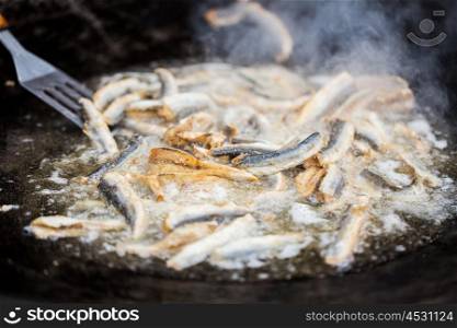 cooking, asian kitchen, sale and sea food concept - close up of fried fish in cast iron pan at asian street market