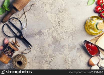 Cooking background: rolling pin, scissors, pepper, garlic, olive oil, eggs, cheese, tomato and basil leaves. Cooking, italian food or vegetarian concept. Top view, copy space