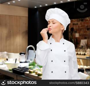 cooking, bakery, gesture and food concept - smiling female chef showing delicious gesture over restaurant kitchen background