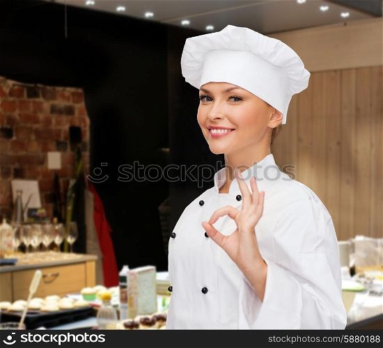 cooking, bakery, gesture and food concept - smiling female chef showing ok hand sign over restaurant kitchen background