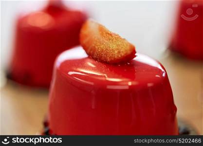 cooking, baking and food concept - close up of strawberry mirror glaze cakes with edible gold at confectionery. close up of mirror glaze cake at confectionery