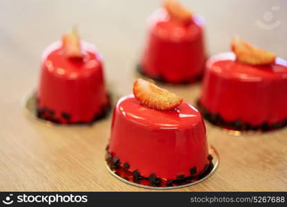 cooking, baking and food concept - strawberry mirror glaze cakes with edible gold at confectionery. strawberry mirror glaze cakes at confectionery