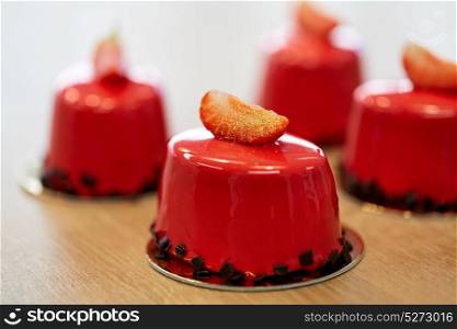 cooking, baking and food concept - strawberry mirror glaze cakes with edible gold at confectionery. strawberry mirror glaze cakes at confectionery