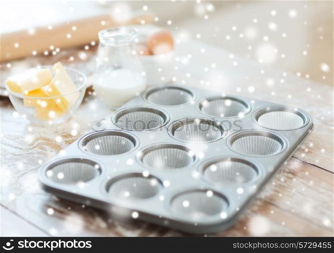 cooking, baking and home concept - close up of empty muffins molds and snow