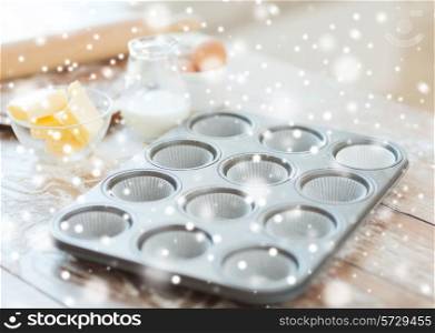 cooking, baking and home concept - close up of empty muffins molds and snow