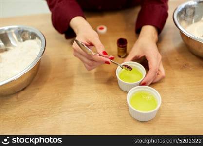 cooking, baking and people concept - chef hands adding food color into bowl with egg whites. chef adding food color into bowl with egg whites