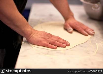 cooking, baking and people concept - chef hands preparing dough on table at kitchen. chef hands preparing dough on table at kitchen