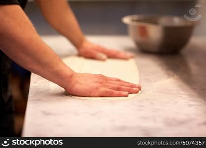 cooking, baking and people concept - chef hands preparing dough on table at kitchen. chef hands preparing dough on table at kitchen