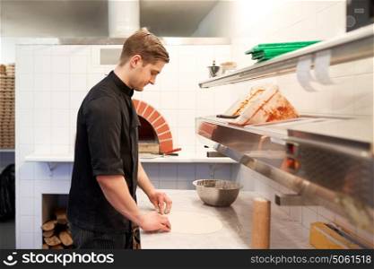 cooking, baking and people concept - chef preparing dough for pizza in kitchen at pizzeria. chef preparing pizza dough in kitchen at pizzeria
