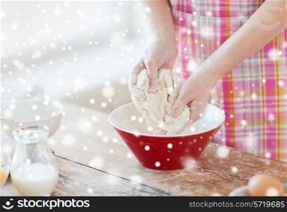 cooking, baking, food, people and home concept - close up of female hands kneading dough in kitchen