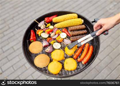 cooking, barbecue and food concept - close up of shish kebab meat, vegetables on bamboo skewers, burger buns with corn and sausages roasting on brazier grill outdoors. barbecue kebab meat and vegetables on grill