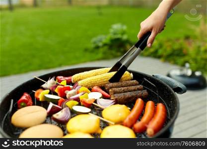 cooking, barbecue and food concept - close up of shish kebab meat, vegetables on bamboo skewers, burger buns with corn and sausages roasting on brazier grill outdoors. barbecue kebab meat and vegetables on grill