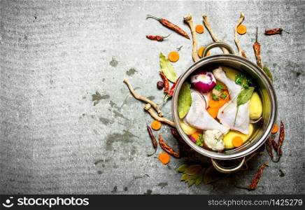 Cooking chicken soup with vegetables in a large pot. On the stone table.. Cooking chicken soup with vegetables in a large pot.