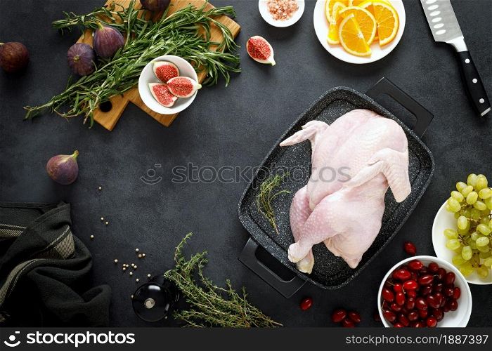 Cooking Christmas turkey with ingredients for cooking on black background, top view. Whole raw turkey preparing for Christmas dinner.
