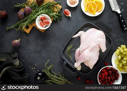 Cooking Christmas turkey with ingredients for cooking on black background, top view. Whole raw turkey preparing for Christmas dinner.