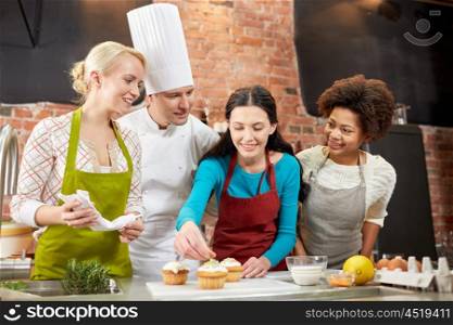 cooking class, culinary, bakery, food and people concept - happy group of women and male chef cook baking in kitchen