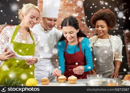 cooking class, culinary, bakery, food and people concept - happy group of women and male chef cook baking in kitchen over snow effect