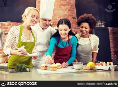 cooking class, culinary, bakery, food and people concept - happy group of women and male chef cook baking in kitchen
