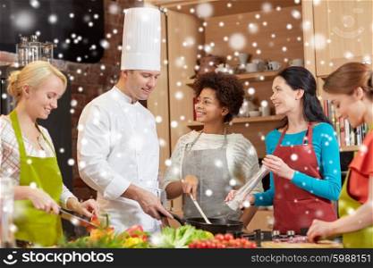 cooking class, culinary, food and people concept - happy group of women and male chef cook cooking in kitchen over snow effect