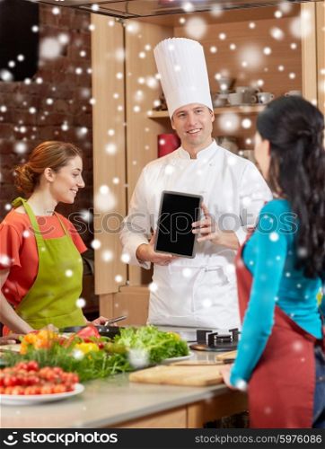 cooking class, culinary, food, technology and people concept - happy women with chef cook showing blank tablet pc screen in kitchen over snow effect