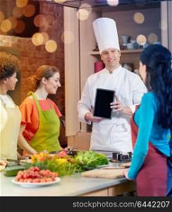 cooking class, culinary, food, technology and people concept - happy women with chef cook showing blank tablet pc screen in kitchen. happy women with chef and tablet pc in kitchen