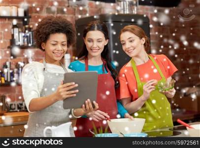 cooking class, friendship, food, technology and people concept - happy women with tablet pc computer in kitchen over snow effect
