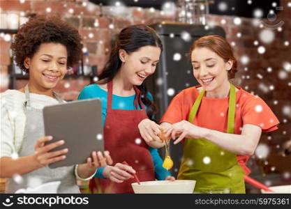 cooking class, friendship, food, technology and people concept - happy women with tablet pc in kitchen over snow effect